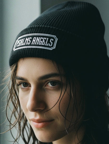 Person wearing a black beanie with 'Psalms Angels' logo against a neutral background